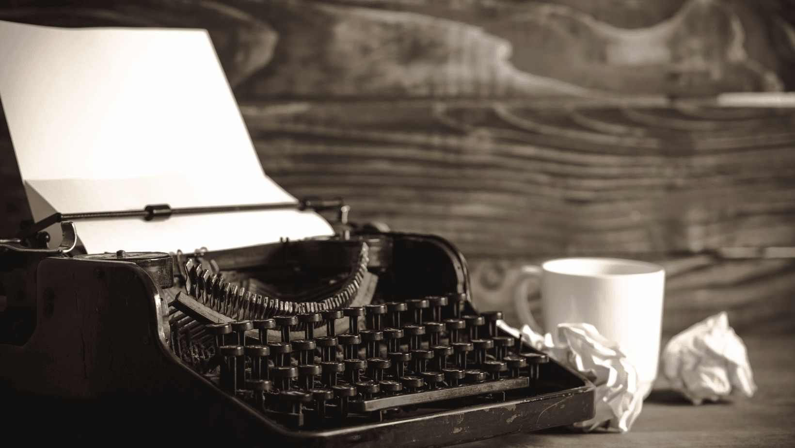 Stock photo of typewriter and mug on desk.